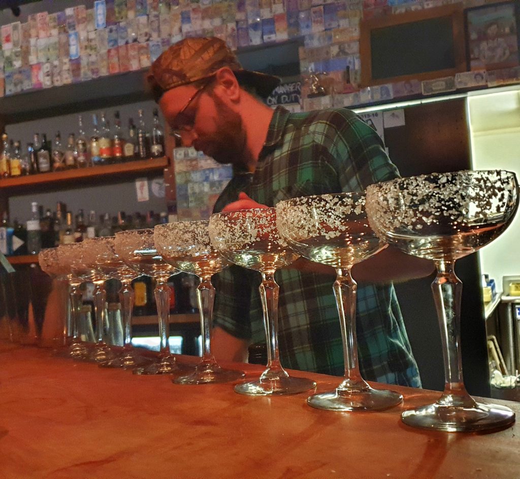 cocktail glasses lined up on a bar